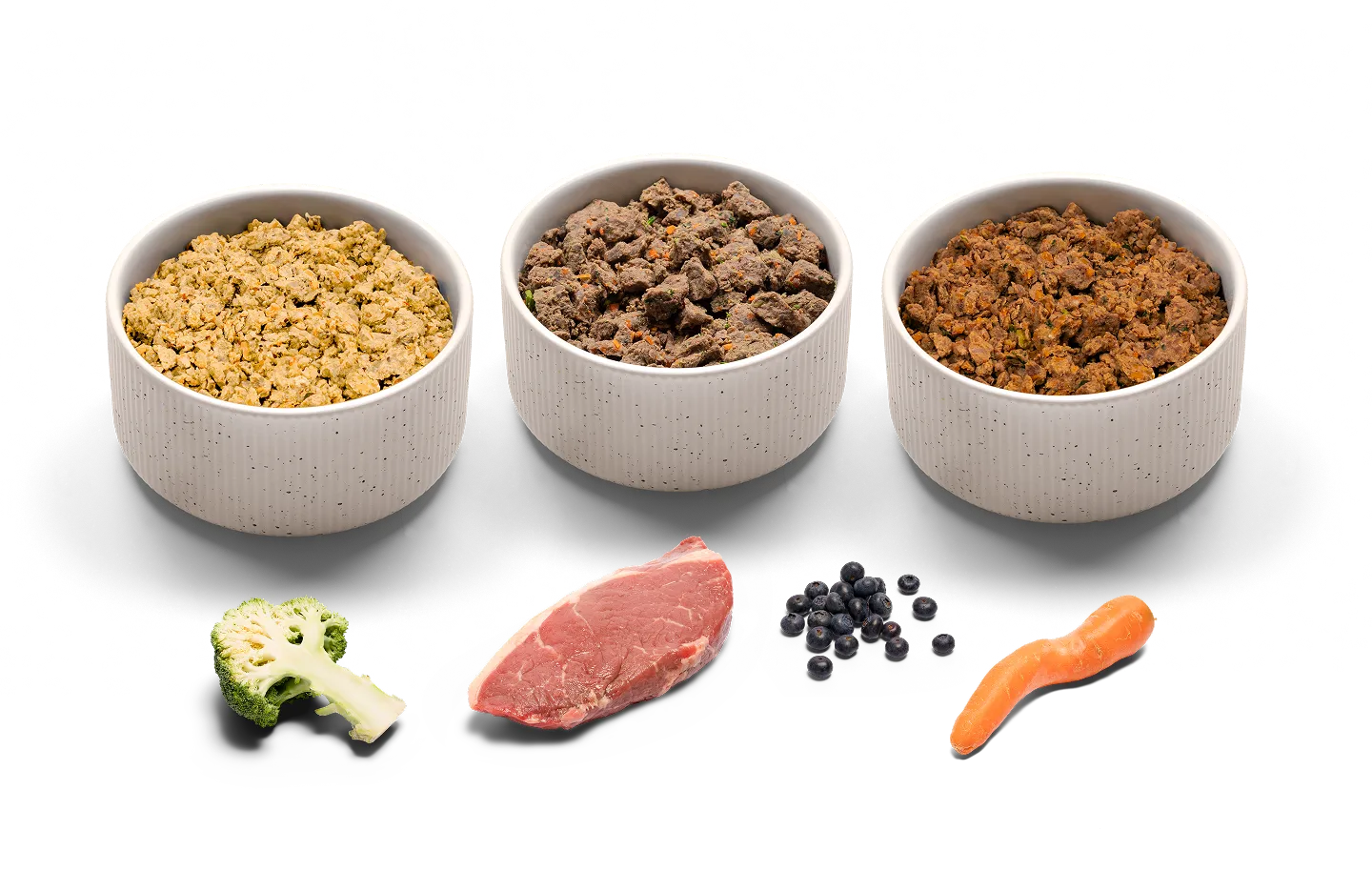 Three different bowls of Lyka with some of their ingredients shown such as broccoli, steak, blueberries and carrots